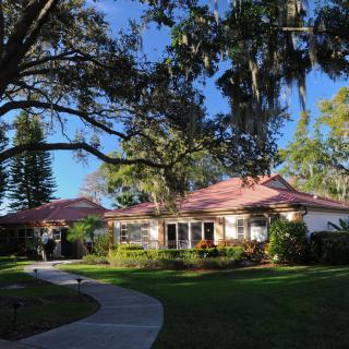 A charming house surrounded by lush greenery and a winding pathway under a clear blue sky.