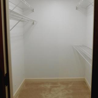 An empty walk-in closet with wire shelving and carpeted floor.