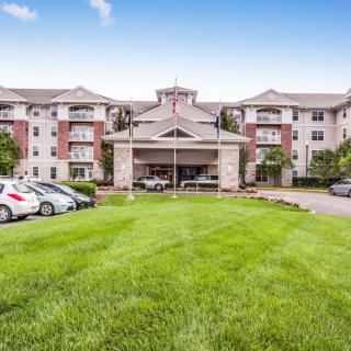 A modern residential apartment complex with a green lawn and parked cars.