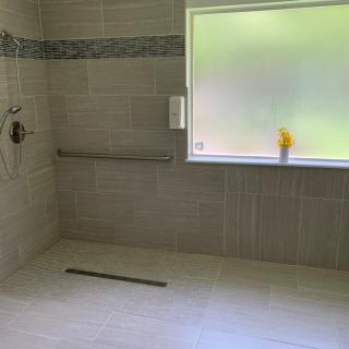 A spacious, modern bathroom with tiled walls and a large shower area.