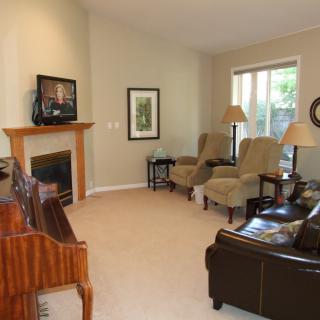 A cozy living room with a fireplace, armchairs, and a piano.