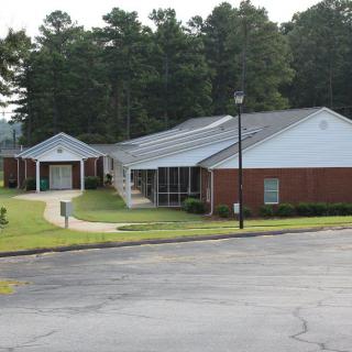 A brick office building surrounded by trees and a paved road.