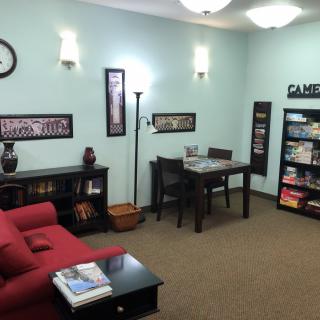 A cozy waiting room with a red sofa, bookshelves, and a candy display.