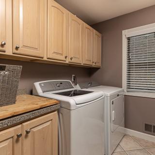 A well-organized laundry room featuring a washing machine, dryer, and wooden cabinets.