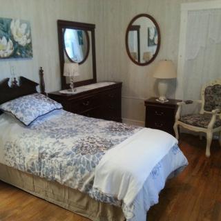 A cozy bedroom with a single bed, wooden furniture, and stylish decor.