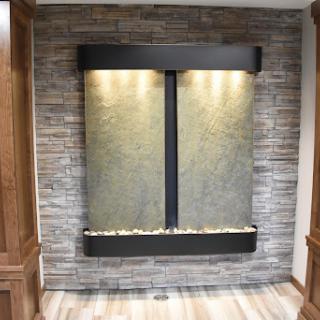 A stylish indoor water feature with ambient lighting, set against a textured stone wall for a modern touch.