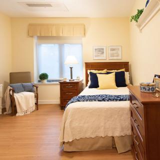 A cozy bedroom with a single bed, wooden furniture, and soft lighting.