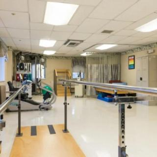 A well-equipped rehabilitation room featuring parallel bars and exercise equipment.