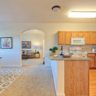 A cozy kitchen opens into a comfortable living room with modern decor and bright lighting.