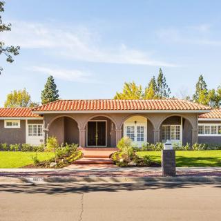 A beautiful single-story house with a tiled roof and front yard landscaping on a sunny day.