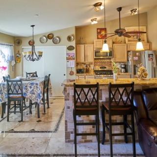 A modern kitchen and dining area with bar stools, chandeliers, and decorative plates on the wall.