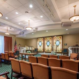 A religious setting with rows of seating and decorative stained-glass windows.