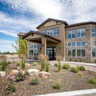 A modern building with large windows and landscaped surroundings under a partly cloudy sky.