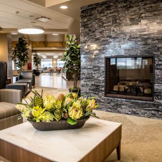 A serene and inviting lobby featuring a modern fireplace and vibrant floral arrangements.