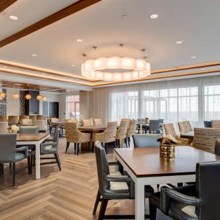 A spacious and elegantly designed dining room with modern furniture and a large chandelier.