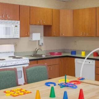 A kitchen with wooden cabinets, appliances, and colorful toys on the table.