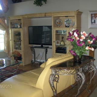 A cozy living room featuring an entertainment center with a television, decorative flowers, and comfortable seating.