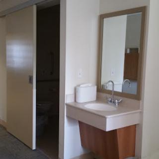 A view of a bathroom featuring a modern washbasin and a mirror, with a door leading to another area.