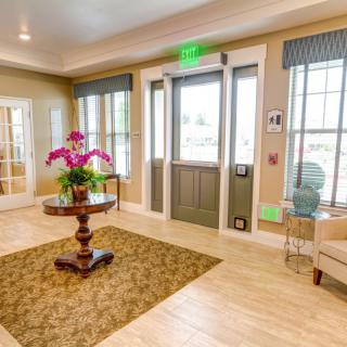 A well-lit lobby with elegant decor, featuring a central table adorned with flowers.