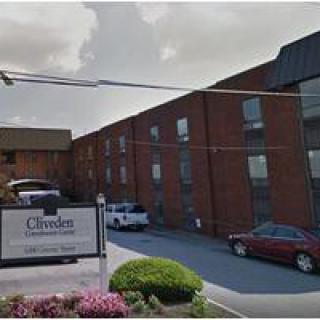 A brick office building with a parking area and signage in front.