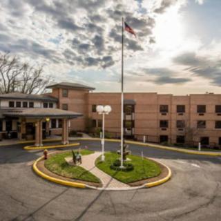 A hospital building with an entrance, American flag, and a cloudy sky.