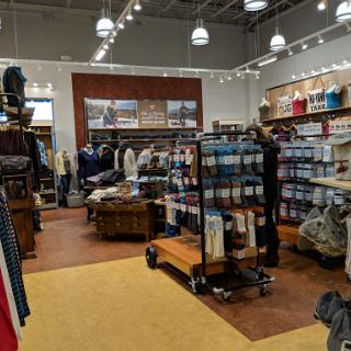 A spacious clothing store interior with neatly arranged merchandise and shoppers browsing.