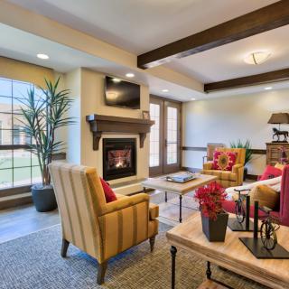 A cozy living room featuring a fireplace, armchairs, and elegant decor with wood beam ceilings.