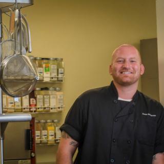 A chef smiling in a professional kitchen setting.