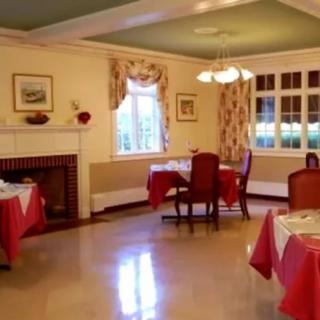 A cozy dining room with elegantly set tables and a warm fireplace.