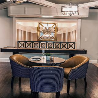 A modern interior dining area featuring stylish chairs and a decorative table with artwork in the background.