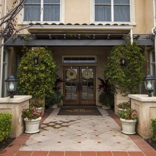 A building entrance with double doors, flanked by potted plants and lanterns.