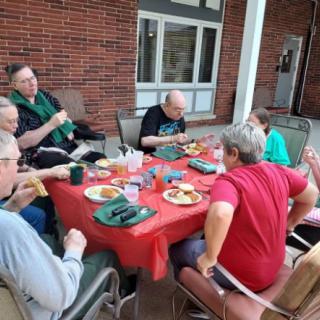 A group of people enjoying a meal together at an outdoor table.