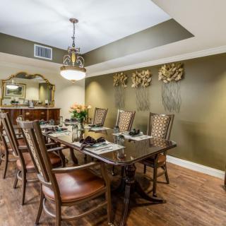 A beautifully decorated dining room with a wooden dining table, chairs, and an elegant chandelier.