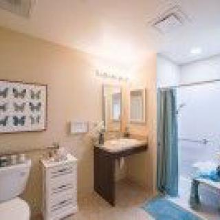 A well-lit bathroom with a sink, mirror, and butterfly artwork on the wall.