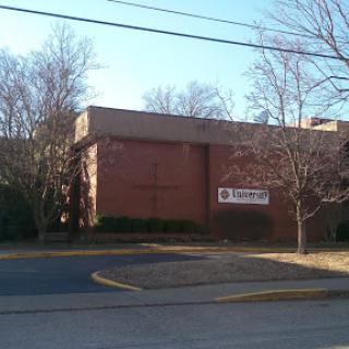 A brick building surrounded by trees on a clear day.