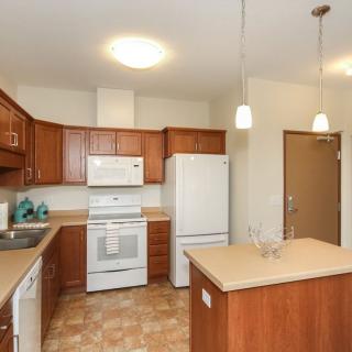 A modern kitchen featuring wooden cabinets, white appliances, and pendant lighting.