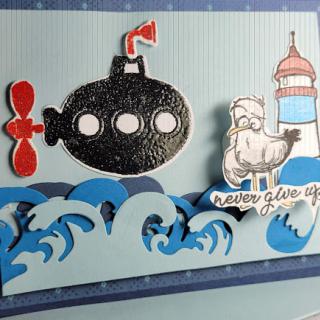 A whimsical handmade card featuring a submarine, a lighthouse, and dynamic waves.