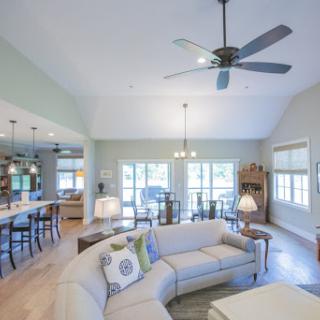 A bright and airy living room featuring an open concept design with a cozy sofa and natural light streaming in.