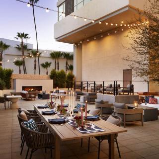 An elegant outdoor patio dining area with string lights and set tables for an evening gathering.