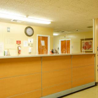A view of a hospital reception area featuring a wooden counter and a clock on the wall.