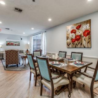 A well-appointed dining room with elegant seating and floral artwork on the wall.