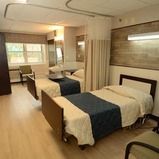 A well-lit hospital patient room featuring two beds and a modern interior.