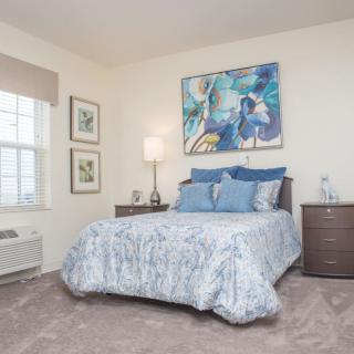 A cozy bedroom with a bed, nightstands, and artwork on the wall.