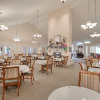 A spacious dining room with elegant chandeliers and neatly arranged tables and chairs.