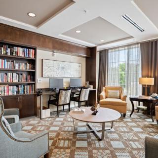 A well-lit reading room featuring bookshelves, comfortable seating, and computer workstations.