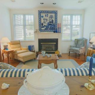 A cozy living room with a central fireplace, surrounded by comfortable furniture and decorated with artwork.