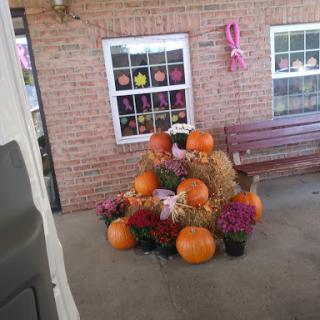 A cozy autumn display featuring pumpkins, hay, and flowers.
