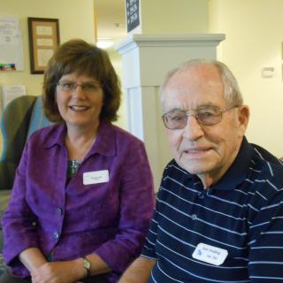 A smiling elderly couple sitting together indoors.