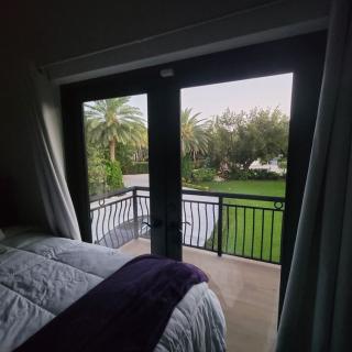 A cozy bedroom with French doors leading to a balcony overlooking a lush garden.