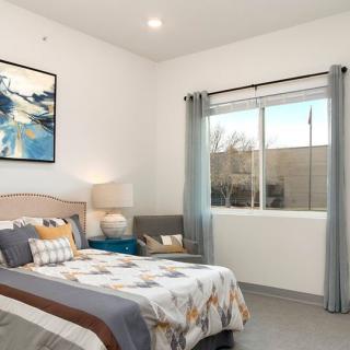 A modern bedroom with stylish decor and a large window providing natural light.